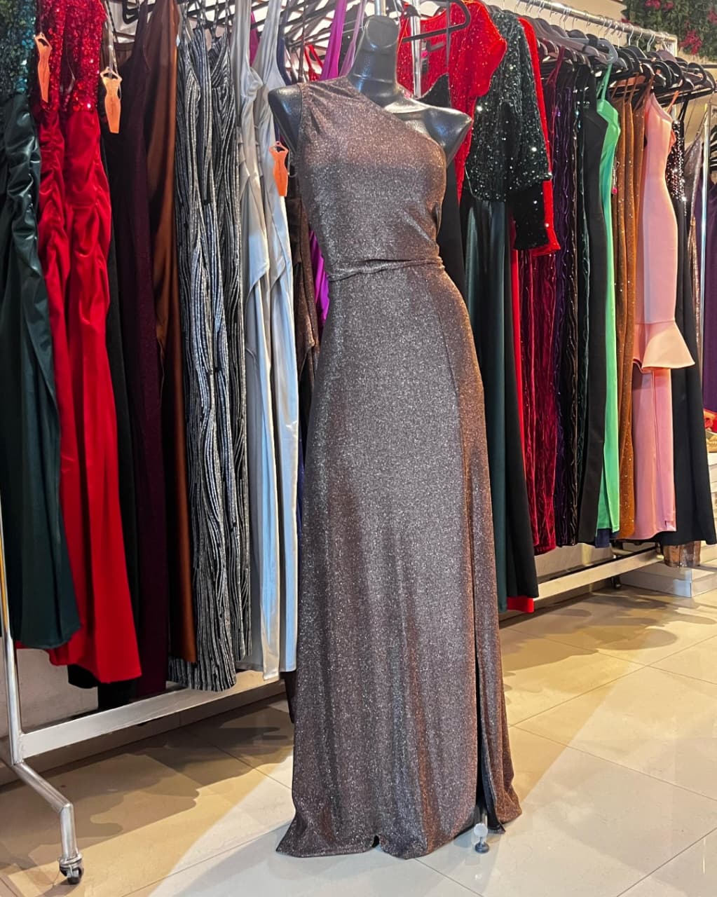 VESTIDO LARGO CON GLITTER COLOR COBRE, DE UN SOLO HOMBRO CON FALDILLA LÍNEA A Y APERTURA EN LA PIERNA